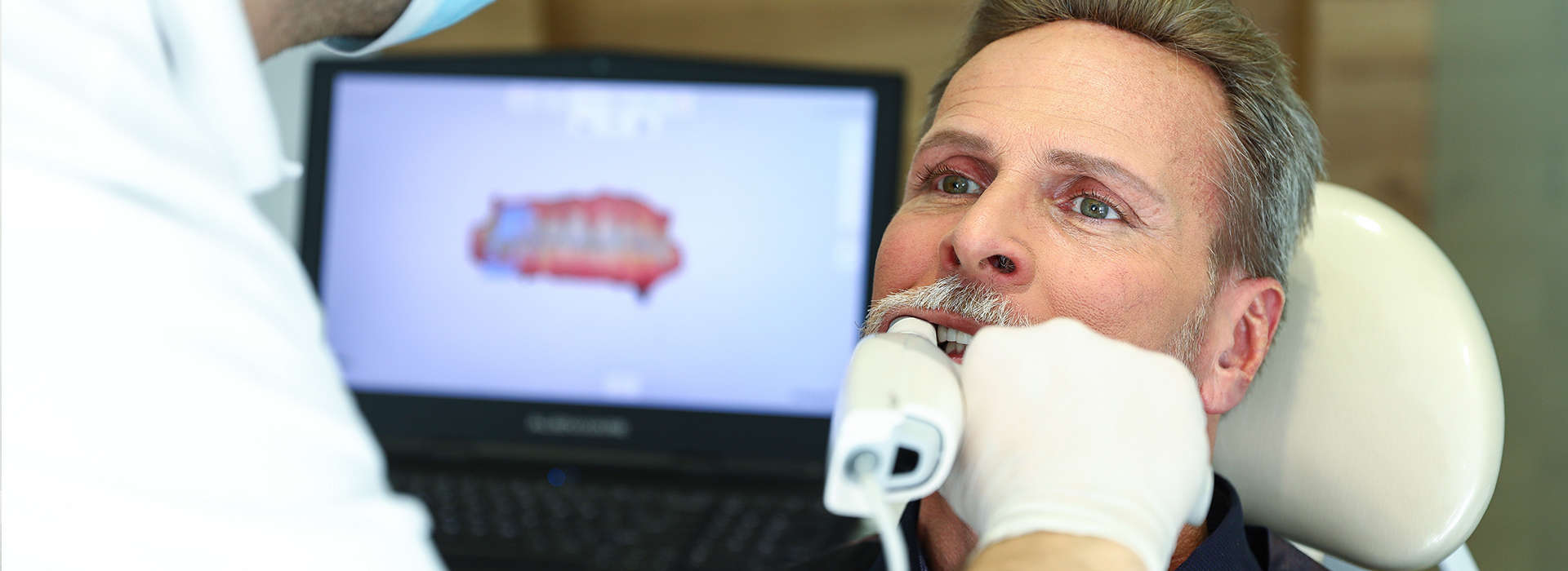 A dentist is performing a procedure on a patient while the patient is seated in a dental chair.