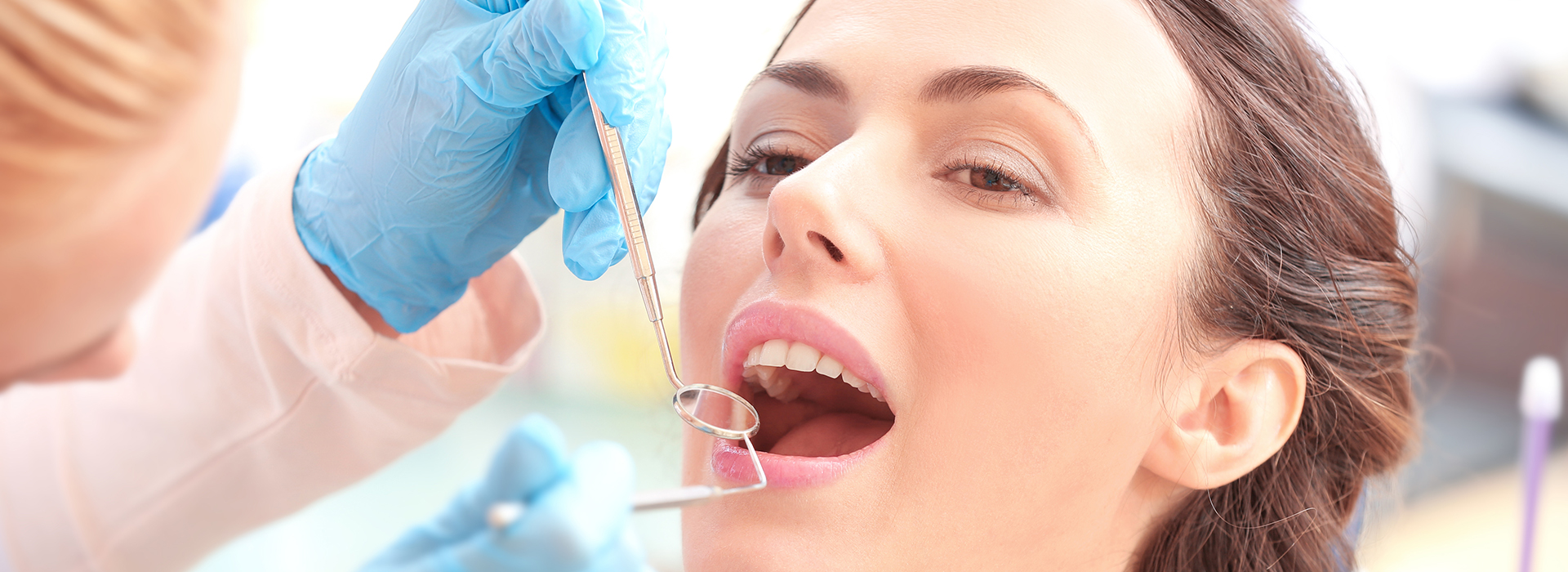 The image depicts a woman receiving dental treatment with a syringe being injected into her mouth by a dental professional, surrounded by other dental professionals assisting in the procedure.