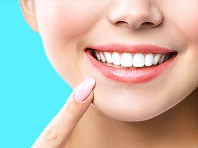 A woman with a radiant smile, showcasing her teeth, against a blue background.